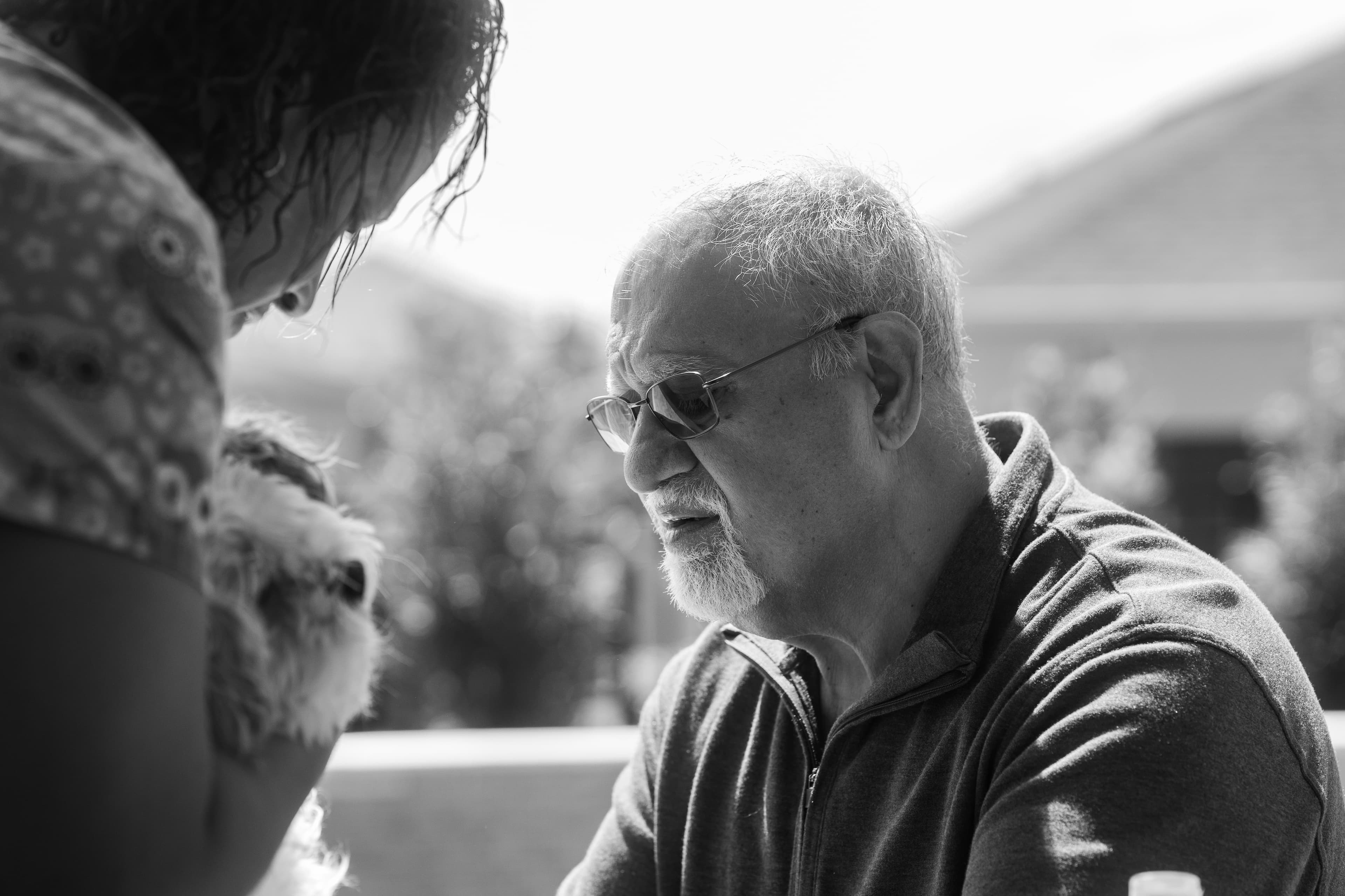 Dr. Khanna looking over his patient on the owner's patio. Gia is carefully holding the animal in place. Photo in black and white.