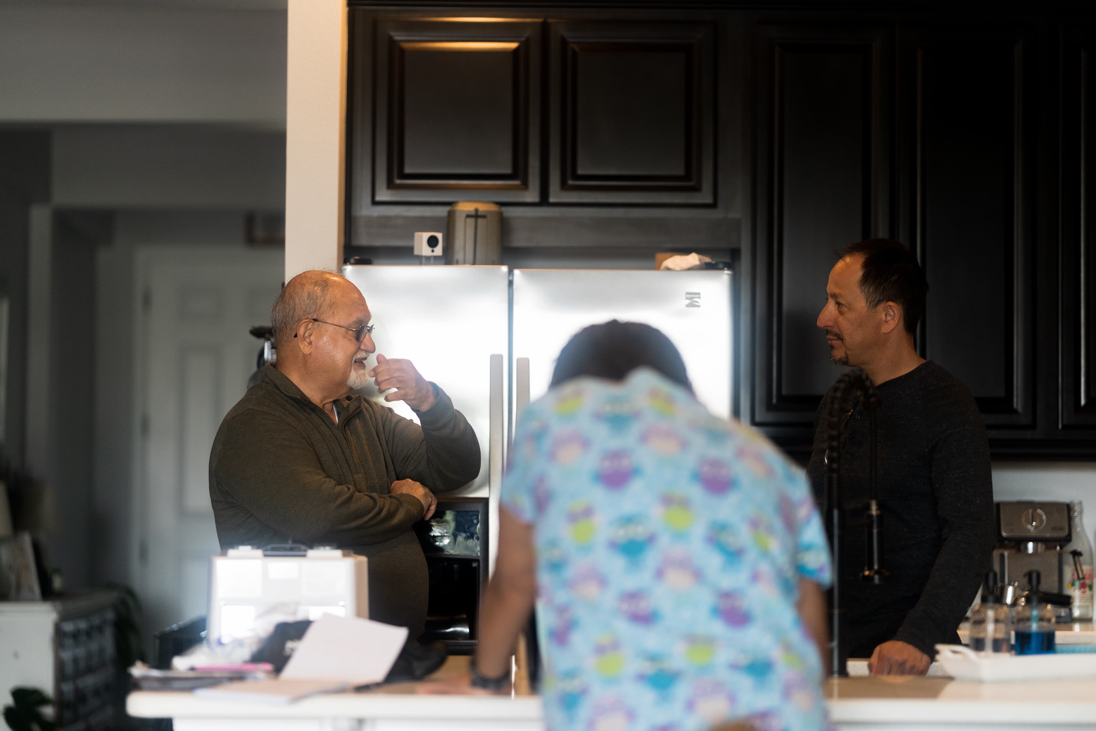 Dr. Khanna and the pet's owner talking in the kitchen while Gia handles the required paperwork. Photo in black and white.