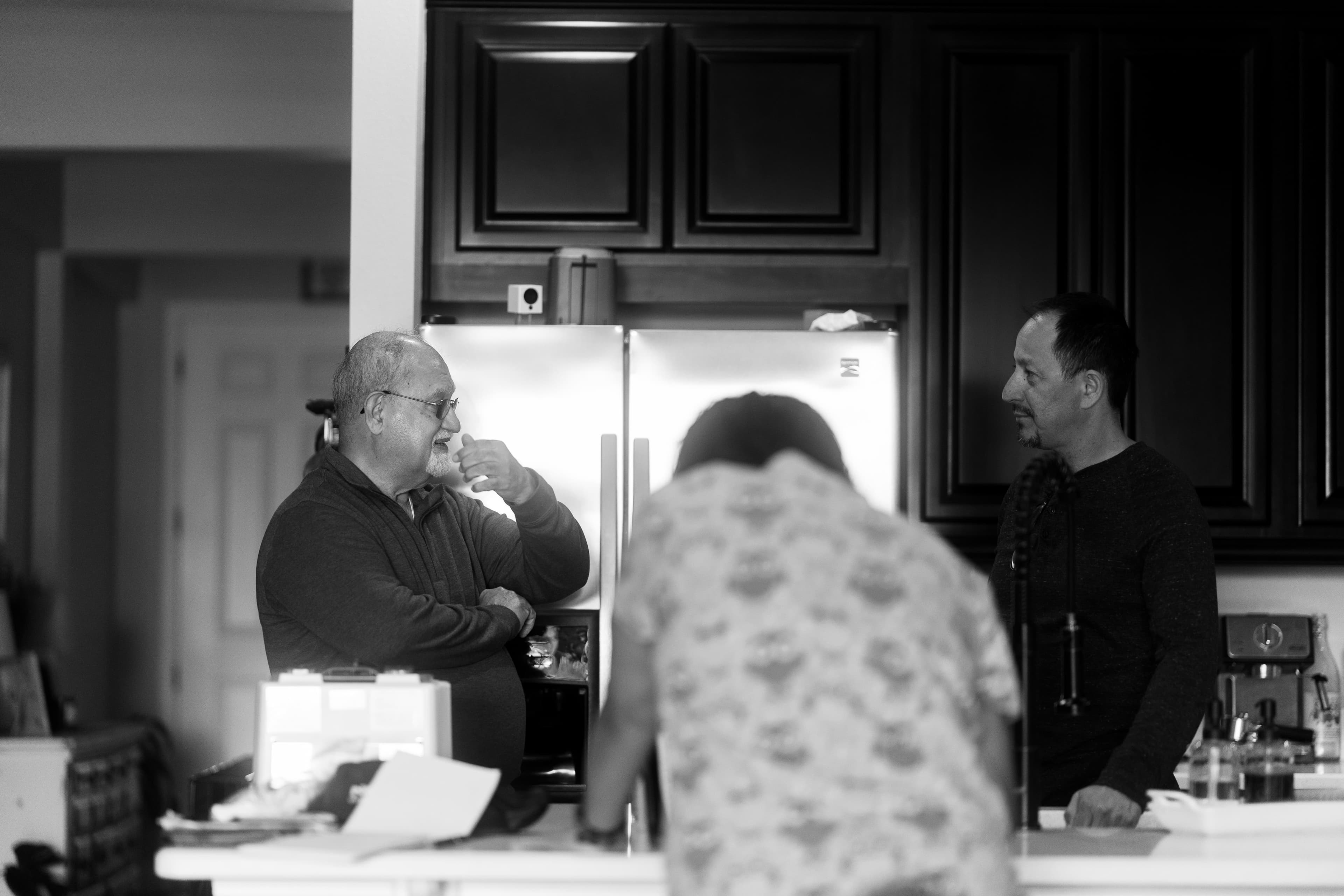 Dr. Khanna and the pet's owner talking in the kitchen while Gia handles the required paperwork. Photo in black and white.